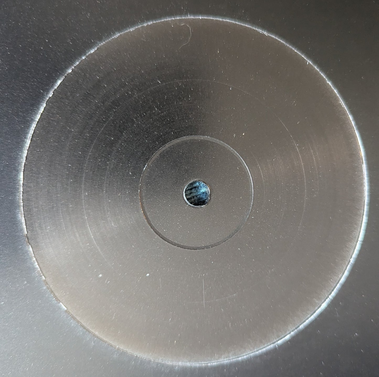 Close-up of a metallic disc with concentric circles and a small central hole.