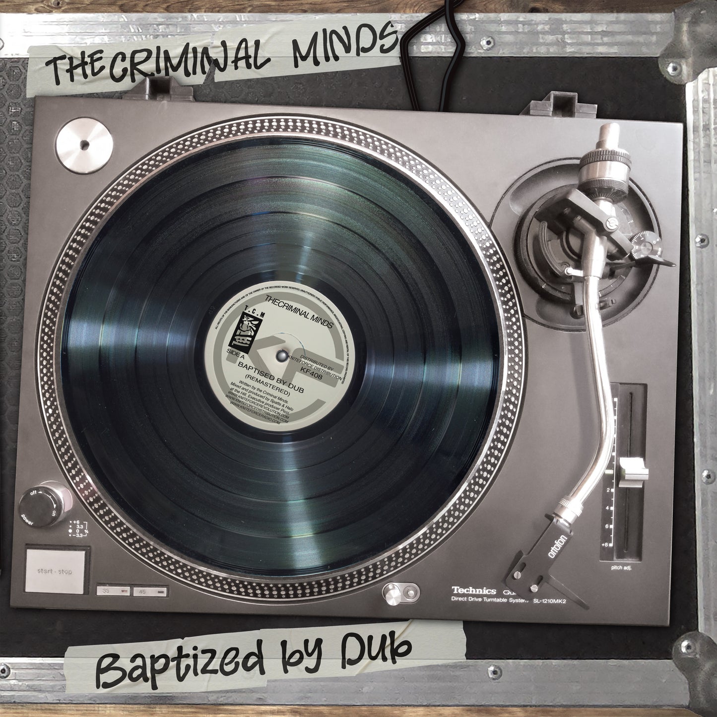 A Technics D-PL70 turntable with a black vinyl record, photographed from above inside a metal case. White handwritten labels read 'THE CRIMINAL MINDS' at the top and 'Baptized by Dub' at the bottom.