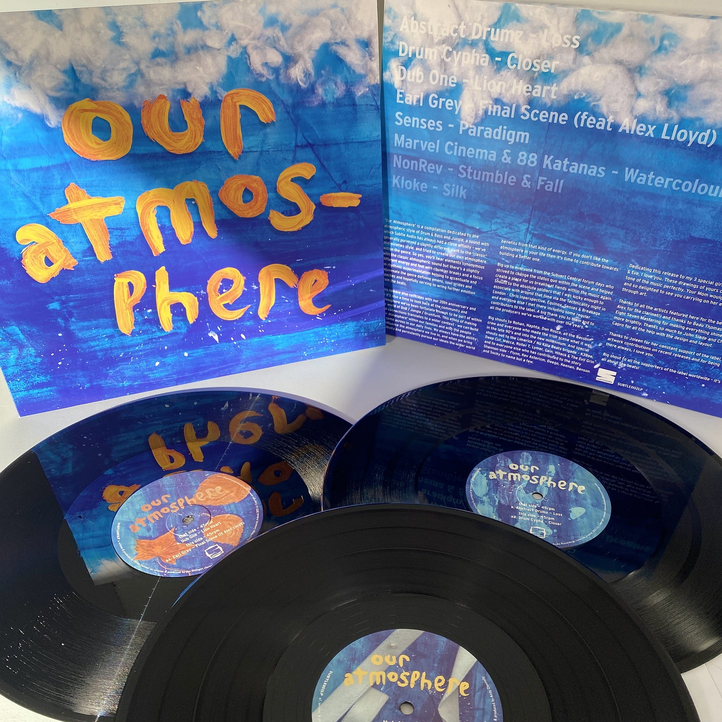 Photo of three records and brightly coloured record sleeve. SUBTLE002LP - Our Atmosphere 3x12" Vinyl