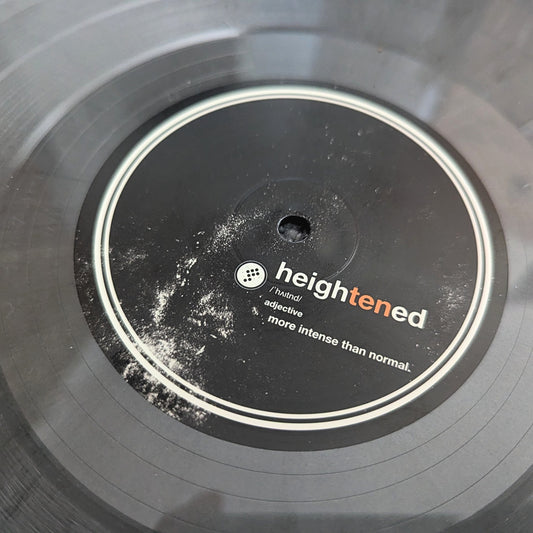 Close-up of a vinyl record label reading 'heightened' with smaller text 'intensive' and 'more intense than normal.' on a dark gray/black record.