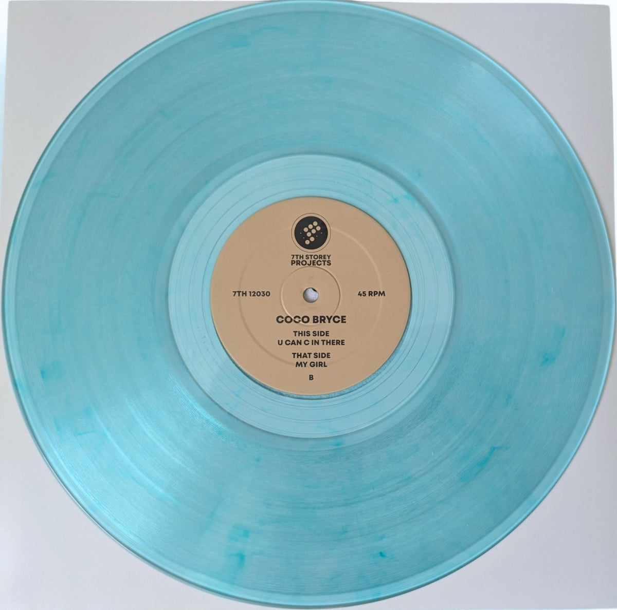A translucent light blue vinyl record with a beige center label, photographed from above on a white background. The label reads Coco Bryce and includes the track title 'U Can't In There That Side My Girl'.