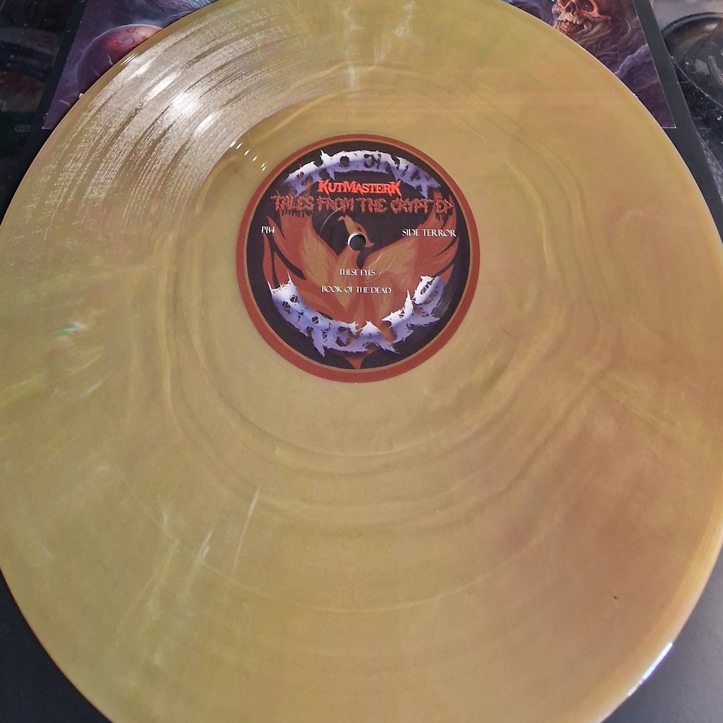 Gold vinyl record with a label featuring text and graphics on a dark surface