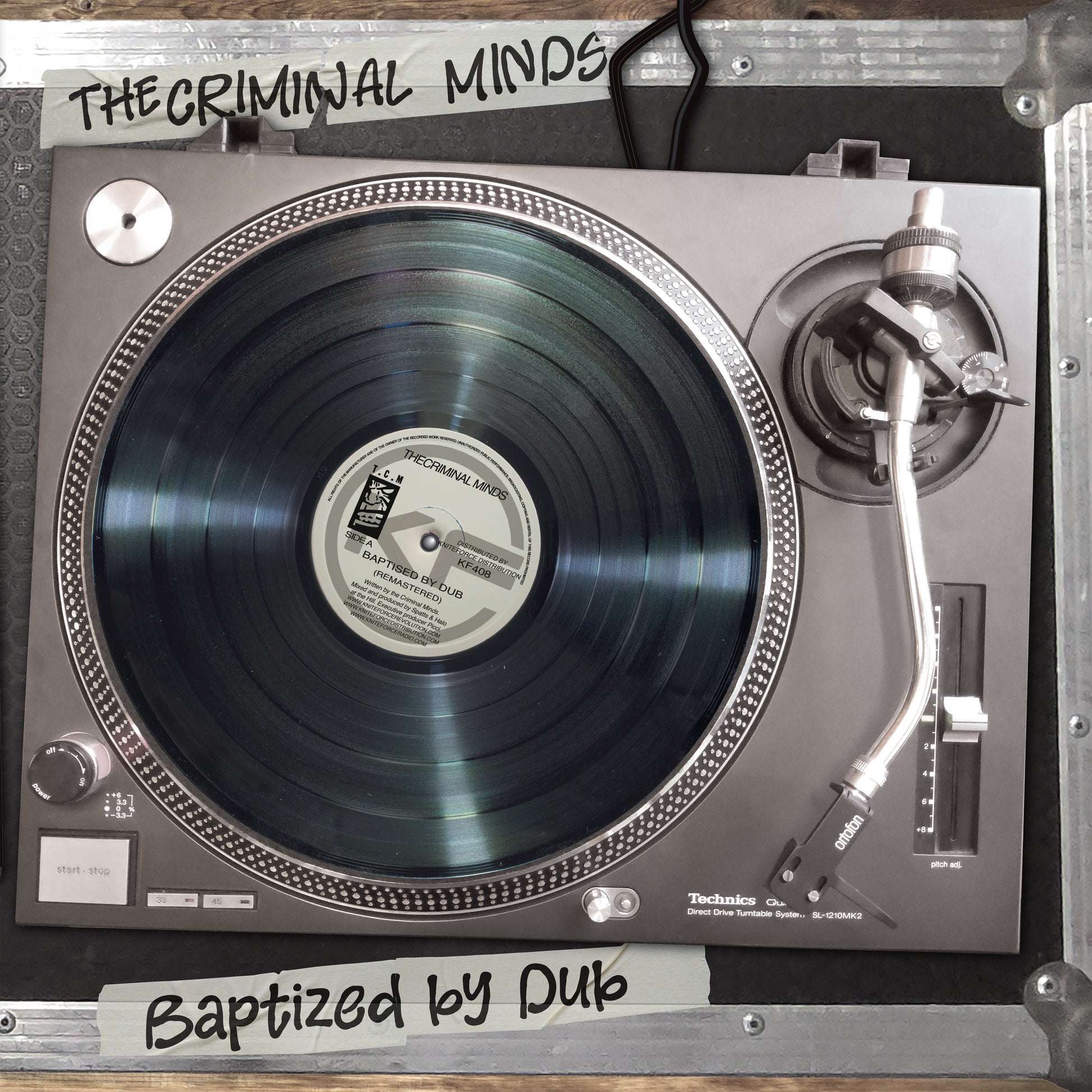 A Technics D-PL70 turntable with a black vinyl record, photographed from above inside a metal case. White handwritten labels read 'THE CRIMINAL MINDS' at the top and 'Baptized by Dub' at the bottom.