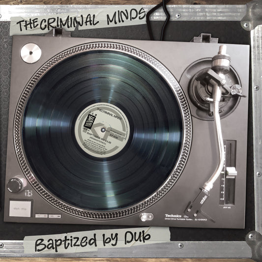 A Technics D-PL70 turntable with a black vinyl record, photographed from above inside a metal case. White handwritten labels read 'THE CRIMINAL MINDS' at the top and 'Baptized by Dub' at the bottom.