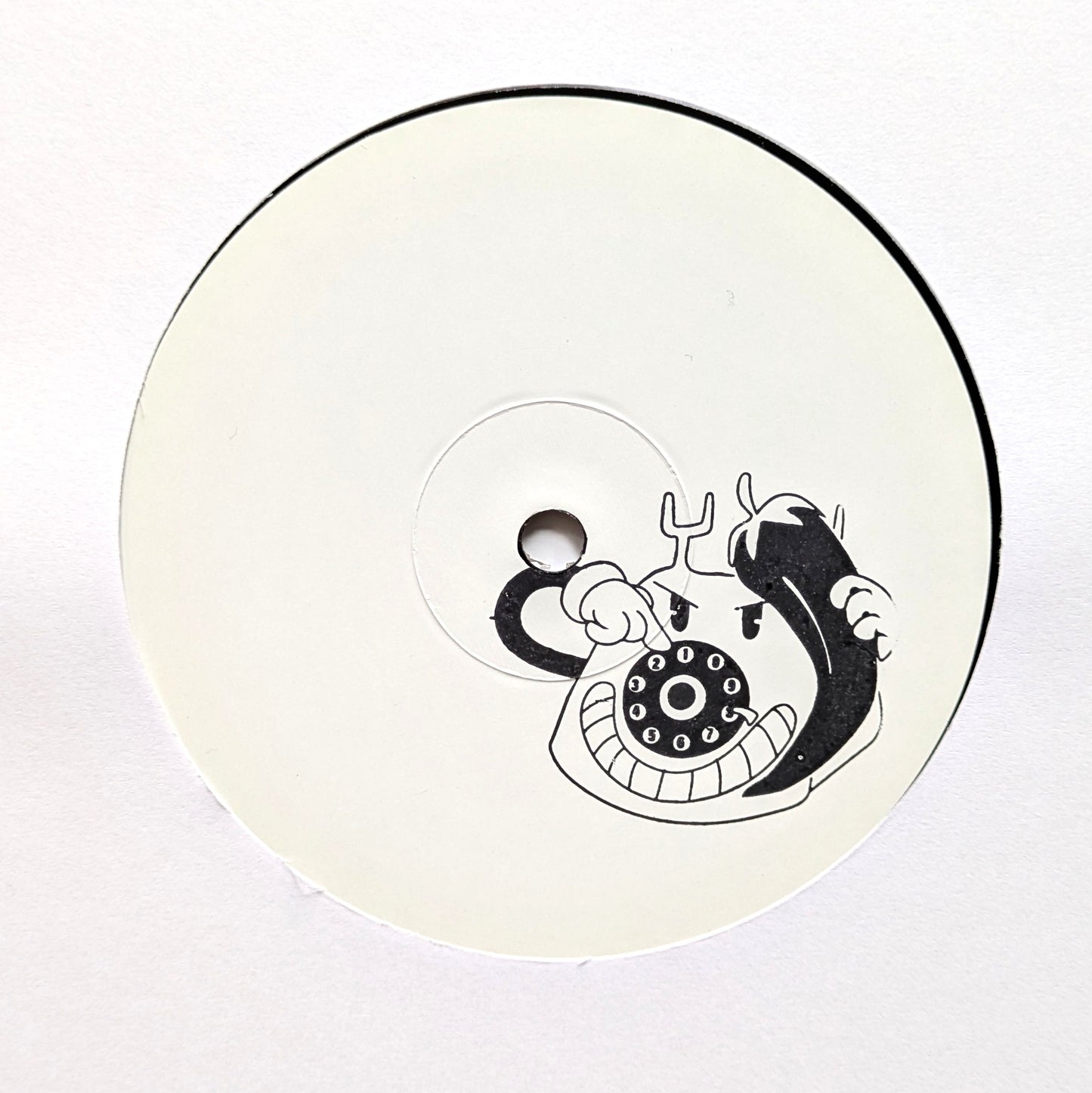 A circular white product, likely a CD, VHS tape, or compact disc, featuring a black graphic of a cartoon character holding a rotary telephone receiver.