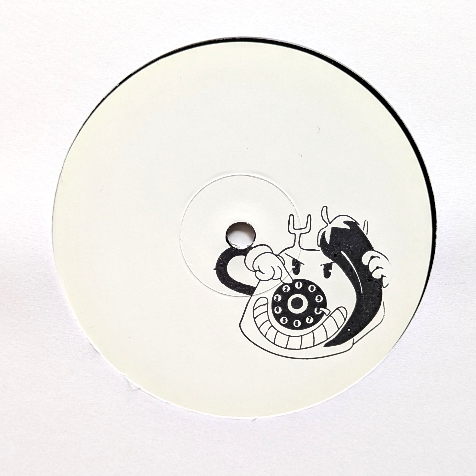 A circular white product, likely a CD, VHS tape, or compact disc, featuring a black graphic of a cartoon character holding a rotary telephone receiver.