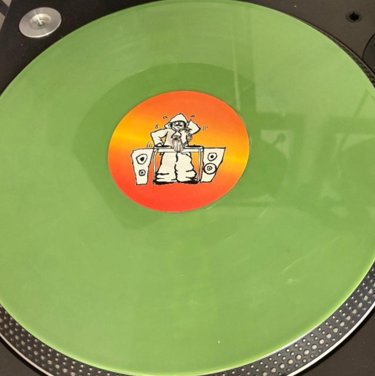 Green vinyl record with a colorful sticker featuring a cartoon character on a turntable.